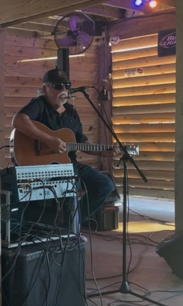 Kokomo Joe performing at a rustic wood-paneled bar